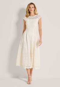 Weißes Spitzen-Midi-Kleid mit kurzen Cap-Ärmeln, floralem Muster, tailliertem Oberteil und schwingendem Rock; mit einem gewellten Saum abschließend.