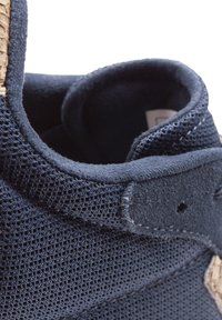 Marinefarbene Mesh-Sneaker mit einem weichen Wildlederkragen, strukturiertem Gewebe und einem kontrastierenden Naturfaserakzent entlang der Seite.