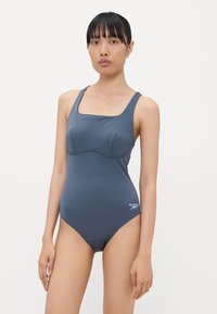 Maillot de bain une pièce gris foncé, avec un décolleté carré, des bretelles larges et une coupe ajustée avec des détails froncés subtils au niveau de la poitrine.