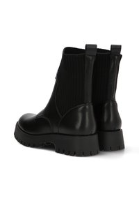 Botas negras hasta el tobillo con un cuerpo de cuero suave, un cuello de tela acanalada y una suela de goma gruesa. Presenta tiradores en la parte posterior.