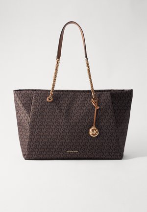 Brązowa torba typu tote z powtarzającym się wzorem "MK", złotym łańcuszkiem i skórzanymi rączkami oraz okrągłą złotą zawieszką z logo Michael Kors.