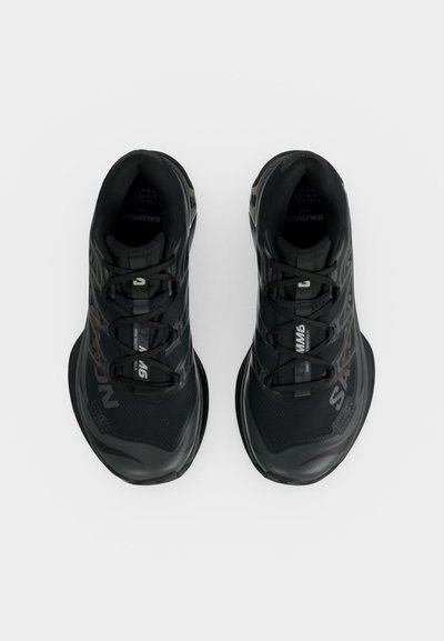 Ζευγάρι μαύρα αθλητικά παπούτσια τρεξίματος με κορδόνια, με την επωνυμία «Salomon», εμφανίζεται από επάνω σε λευκό φόντο.