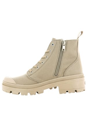 Beige high-top canvas boot with lace-up front, side zipper, rubber toe cap, thick tread sole, and heel loop tab.