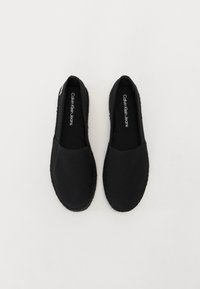 Espadrillas nere in tela con una suola texturizzata, caratterizzate da un design semplice e dal logo del marchio all'interno della scarpa.