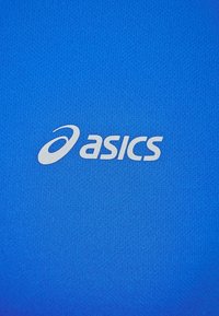 Sininen urheilupaita, jossa on valkoinen "asics"-logo keskellä, kerecoituna kosteutta siirtävään materiaaliin. Suora ja vartalonmyötäinen muotoilu.