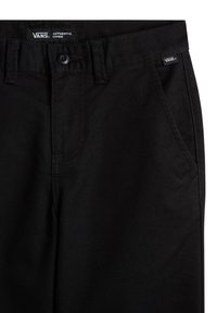 Pantalon chino noir en coton avec une texture lisse. Comprend une fermeture à bouton, des passants de ceinture et deux poches avant. Étiquette "VANS" sur la ceinture.