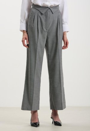 Pantaloni grigi a vita alta con finitura testurizzata, pieghe sulla parte anteriore e gambe larghe. Abbinati a décolleté nere a punta.