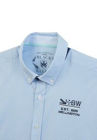 Chemise habillée bleu clair avec un motif à pois, col boutonné, logo brodé et détails intérieurs de col contrastants.
