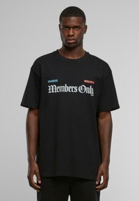 Sort bomulds T-shirt med oversized pasform, der har fed hvid og farvet tekst "Kun for medlemmer" samt yderligere grafikker i blåt og rødt.