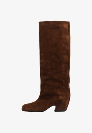 Bota alta de ante marrón con punta redondeada, tacón bloque afilado y textura lisa. Presenta costuras sutiles a lo largo del lateral.