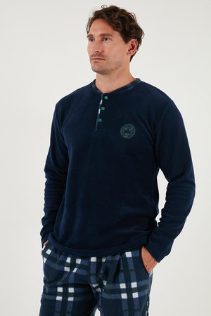 Marineblaue Fleece-langärmlige Shirt mit geknöpfter Halslinie und waldgrünen Akzenten; getragen mit karierter Fleece-Hose in Dunkelblau, Weiß und Grün.