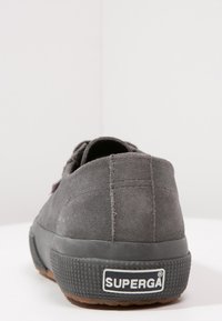 Grå mocka sneakers med gummisula, med strukturerad detaljering och en framträdande "SUPERGA"-logga på hälen.