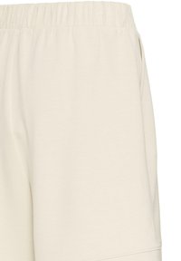 Short beige avec taille élastique et poches latérales, confectionné en tissu doux, présenté sur fond blanc.