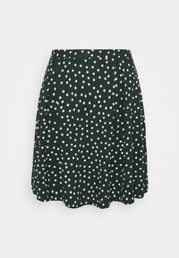 Jupe patineuse verte à pois blancs. Comprend des plis, une texture lisse et une forme évasée. L'ourlet est légèrement arrondi.