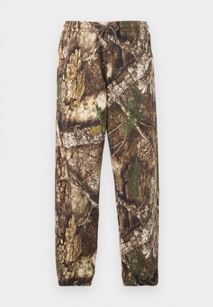 Pantalones de chándal de camuflaje con un patrón natural en tonos marrón y verde, que cuentan con una cintura elástica con cordón y puños elásticos en los tobillos.