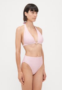 Set bikini a righe rosa e bianche, con top a halter neck e dettaglio anello centrale, e bottom a vita alta. Tessuto di texture liscia.