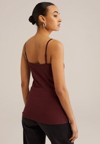 Bordeaux-nuotti tank top tenkeillä harteilla, valmistettu pehmeästä puuvillakankaasta. Ominaisuuksia ovat istuva muotoilu ja sileä pinta, joka ulottuu lantiolle.