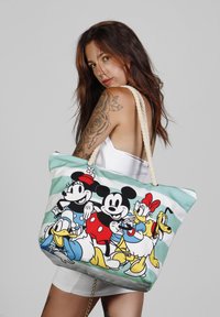 Bolsa de lona con un estampado colorido de personajes de Disney sobre un fondo de rayas en color menta, con asas de cuerda y un cierre de cremallera.