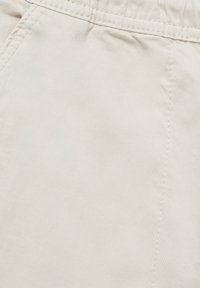 Beige cotton fabric with a smooth texture, featuring discreet stitching and a clean finish; focused on comfort and wearability.