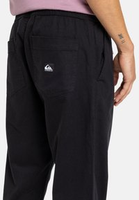 Čierne nohavice vyrobené z bavlny, s voľným strihom, dvoma zadnými vreckami a malou logom na pravom vrecku.