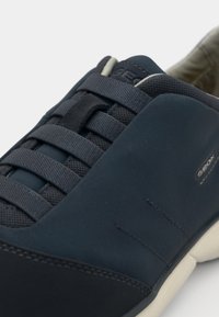 Dunkelblauer Sneaker mit strukturiertem Obermaterial, flachen Schnürsenkeln und Gummisohle. Verfügt über ein Logodetail und glatte Akzente an den Seiten.