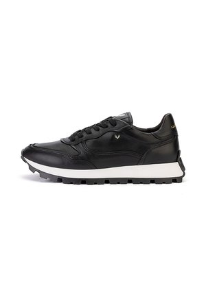 Zapatilla negra de caña baja con suela blanca, cordones negros, suela exterior texturizada y pequeño logo en el lateral, mostrada desde el lado exterior.