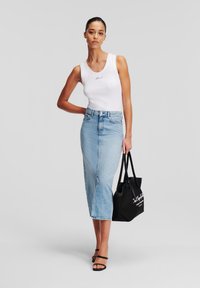 Bela majica brez rokavov z vezenimi detajli, svetlo modra denim midi krila, črn toaletni nahrbtnik in črne sandale z naramnicami. Gladko blago in sproščen dizajn.