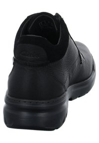 Black leather shoe with a textured finish, cushioned sole, and low ankle height. Features a round toe and a discreet logo on the heel.