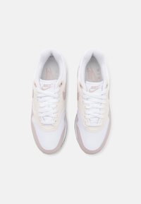 Sneakers Nike Air con tomaia in mesh bianco e sintetico, dettagli rosa pallido, lacci bianchi piatti, punta arrotondata e colletto imbottito.