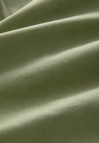 Textilní látka v tlumené olivově zelené, s hladkou texturou a viditelným diagonálním vzorem tkaní, splývající v jemných, plynulých nabídkách.