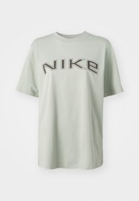 Ljusgrön bomullströja med en djärv svart "NIKE"-logotyp. Kortsleeve och rund hals kännetecknar dess enkla, avslappnade passform.