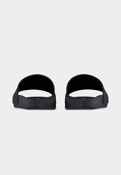 Fekete, széles pántos, lapos talpú papucs párja, elölről világos, egyszerű háttéren bemutatva.