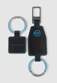 Llavero de cuero negro con herrajes plateados, que presenta una etiqueta rectangular y dos anillos, acentuado con costuras azules y detalle de logo.