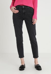 Mustat denim-farkut slim fit -mallilla ja suoraa lahjetta, joissa on taskut ja nappisuljenta, yhdistettynä kirkkaan pinkkiin ribbipaitaan.