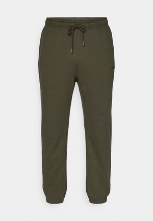 Pantalones de chándal verde oliva con cintura elástica y cordón ajustable. Puños ajustados en los tobillos, tejido suave, minimalismo en la marca en el lateral.
