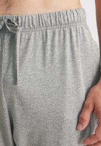 Grijze katoenen loungebroeken met een elastische tailleband, trekkoord detail en een gladde textuur. Kenmerken een ontspannen pasvorm en een minimalistisch ontwerp.