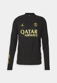 Haut de sport noir à manches longues avec logo jaune Qatar Airways, écusson Paris Saint-Germain, logo Jordan et col avec fermeture éclair au quart.