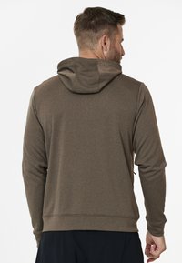 Sweat à capuche brun en tissu lisse. Il possède des manches longues, une poche arrière et un ourlet ajusté. Design simple sans motifs visibles.