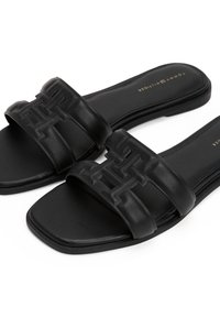 Sorte læder slip-on sandaler med prægede geometriske remme og firkantet tå, mærket med Tommy Hilfiger-logo på indersålen.