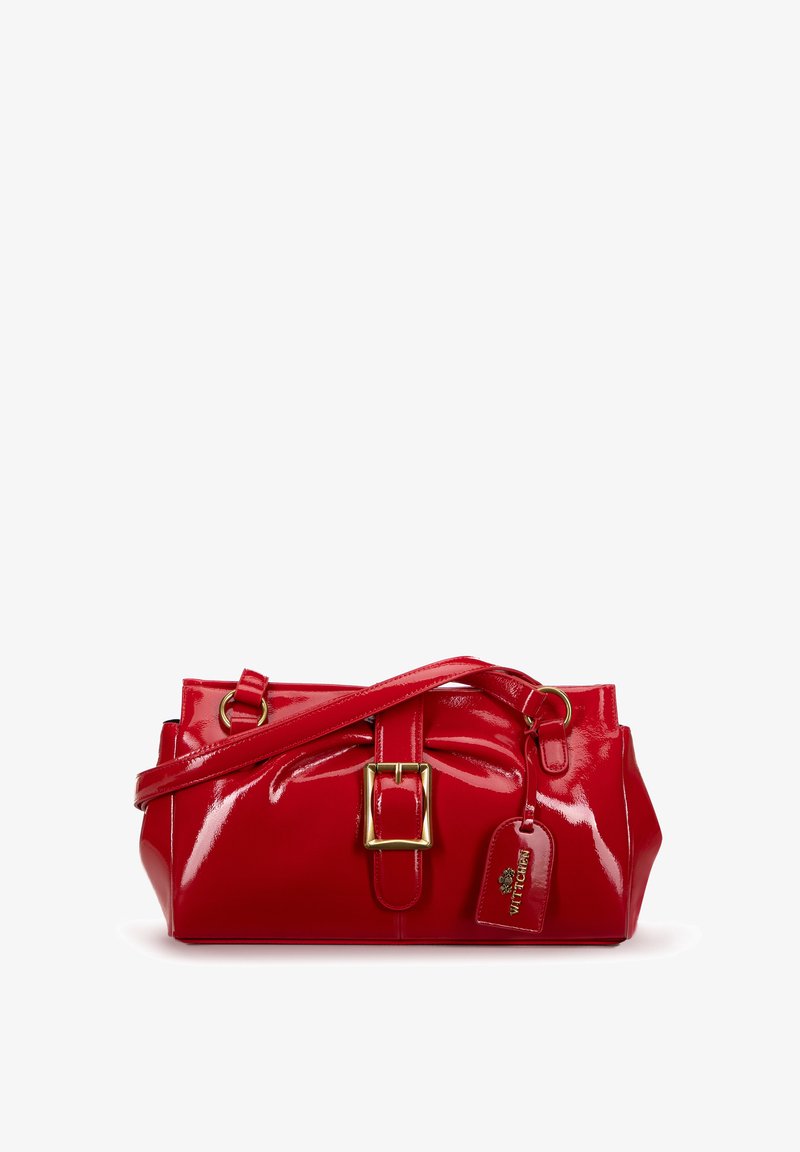 Sac à main en cuir verni rouge avec une forme structurée, une boucle en métal doré, une bandoulière ajustable, et une étiquette amovible arborant un logo.