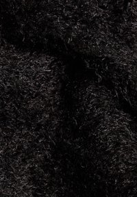 Gros plan sur un tissu noir bouclé, doux et dense, avec une surface texturée et duveteuse et un éclat naturel subtil.