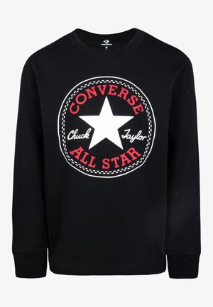 Chemise noire à manches longues avec une grande étoile blanche et un texte rouge indiquant ""Converse All Star"" ainsi qu'un texte cursif blanc ""Chuck Taylor"" sur le devant.
