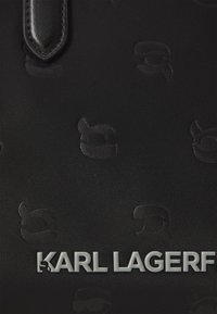 Black fabric handbag with embossed Karl Lagerfeld logo and patterns. Features a smooth texture and rectangular shape, with silver hardware.
