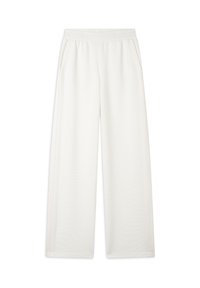 Pantaloni della tuta a gamba larga in tessuto crema, con due tasche laterali, un elastico in vita e una leggera trama a coste lungo il tessuto.