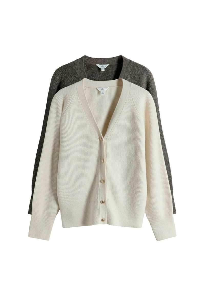 Lys beige ribbet cardigan med V-hals og guldfarvede knapper, lagdelt over en mørkegrå cardigan med et lignende design og tekstur.