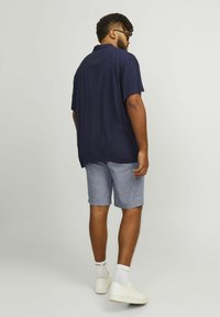 Chemise courte à manches courtes bleu marine avec une coupe décontractée, associée à un short gris. La chemise présente une texture subtile, tandis que le short est léger et décontracté.