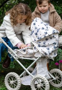 I bambini interagiscono con un passeggino giocattolo in metallo grigio chiaro, dotato di grandi ruote, una copertura in tessuto decorato con mongolfiere e un fondo in rete.