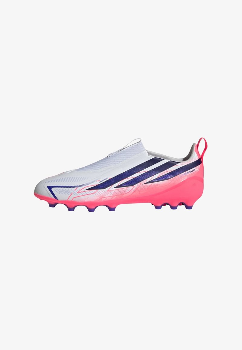 Bota de fútbol blanca y rosa con rayas negras, parte superior sin cordones y suela con tacos para jugar en terreno firme.