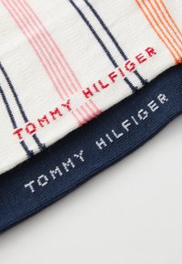 Katoenen breisel met rode, roze en marineblauwe strepen. "TOMMY HILFIGER" logo geborduurd in rood en wit op contrasterende secties.