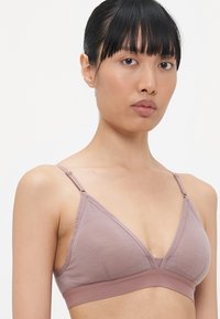 Lila trådlös bralette med en triangulär form, mjuk bomullsmaterialblandning, justerbara remmar och ett brett elastiskt band under bysten.